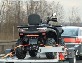 Bil drar ett släp med en fyrhjuling på motorväg