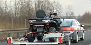 Bil drar ett släp med en fyrhjuling på motorväg