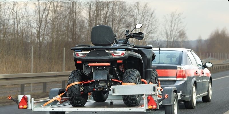 Bil drar ett släp med en fyrhjuling på motorväg